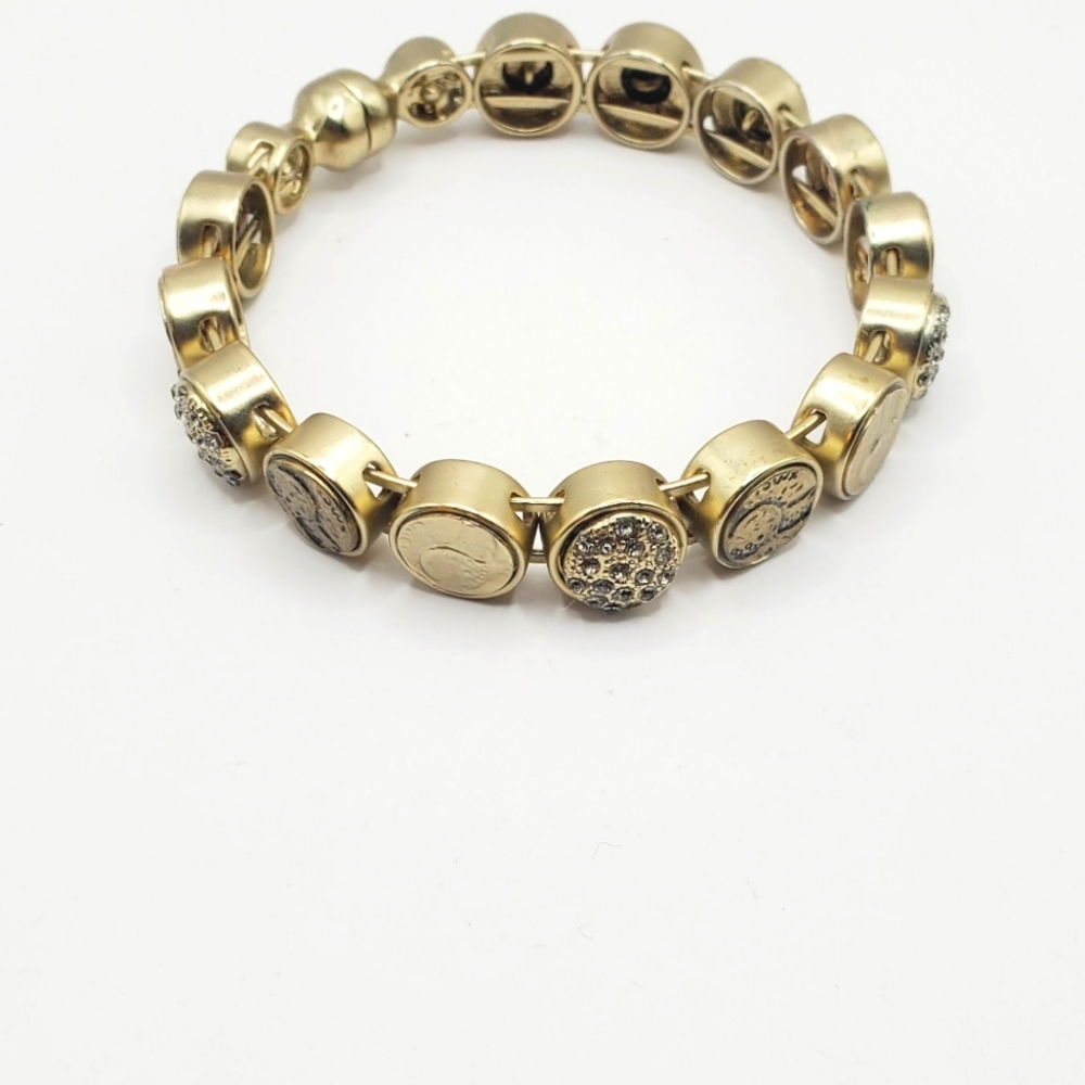 Golden bangle bracelet crafted with laser-etched "coin" medallions and faux-diam
